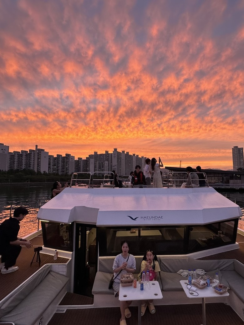 在火紅晚霞下坐在甲板上的旅客們