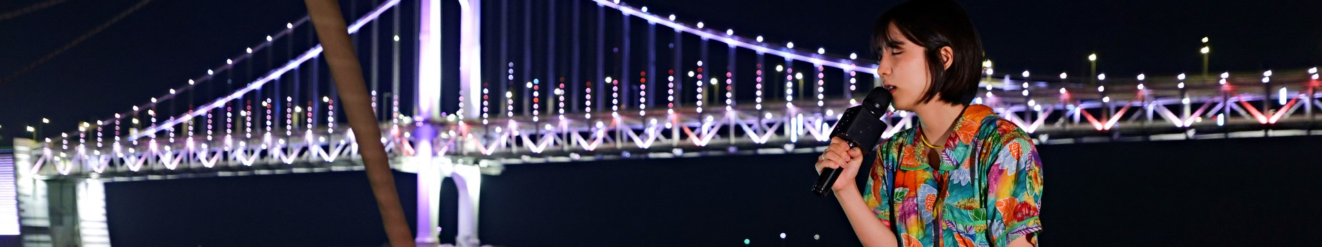 以廣安大橋為背景，在遊艇船頭唱歌的街頭藝人