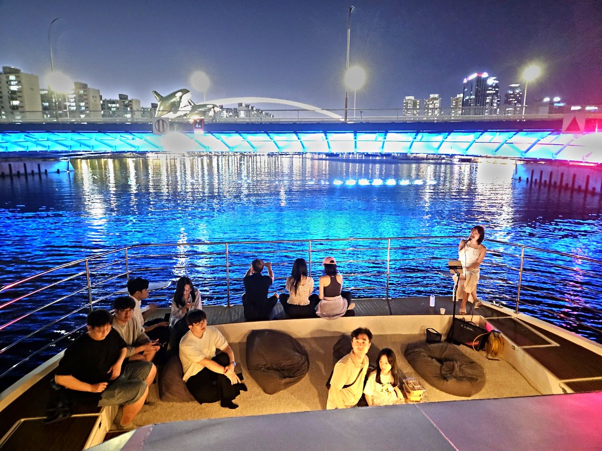 無人機秀上演時,夜海上船頭甲板的團體旅客