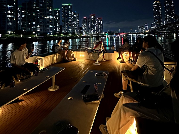 以夜景為背景聚在甲板上的團體旅客